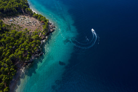 Tourist boat on the emerald sea from a bird's eye view, beautiful coastline covered with thick trees. Makarska riviera in Dalmatia, Croatiaの写真素材