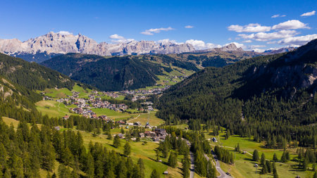 Amazing drone view of idyllic landscape in the Dolomites with fresh green meadows, cozy village houses and majestic mountain peaks.の写真素材