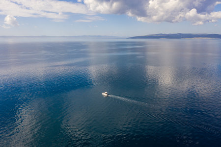 Tourist boat on the emerald sea from a bird's eye view, huge clouds and, on the horizon, a beautiful coastline. Makarska riviera in Dalmatia, Croatiaの写真素材
