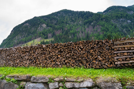Stacked split logs. Pile of logs ready for winter. Wooden stumps, firewood, piled in a beautiful mountain landscape. High Tauern. Grossglockner National Park. Austriaの写真素材