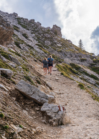 Two girls are walking along the mountain road. Dolomites, Dolomites. Italy, South Tyrolの写真素材