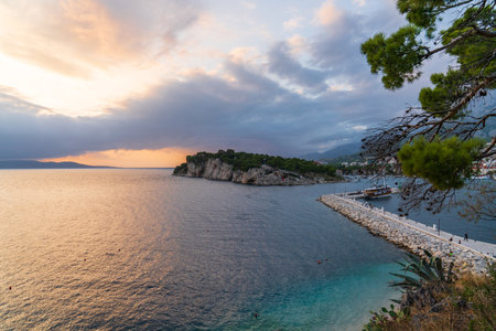 Beautiful sunset on the sea. Tourist wooden ship moored. Orange clouds in sunset sky. Croatian coastline. Makarska. Summer vacation.の写真素材