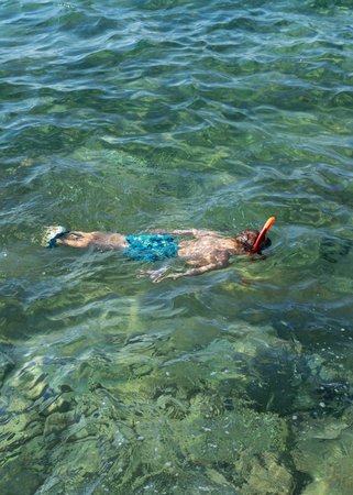 Happy little boy in a diving mask diving underwater and looking at underwater world. Family lifestyle, travel. Swimming on a beach holiday with a child.の写真素材