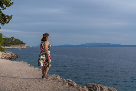 A woman stands on the seashore and looks into the distance. Before sunset.の写真素材