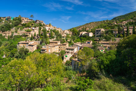 Stunning cityscape of the small coastal village of Deia in Mallorca, Spain. Traditional houses terraced on hills surrounded by green trees. Tourist destinations in Spain. Balearic Islands.の写真素材