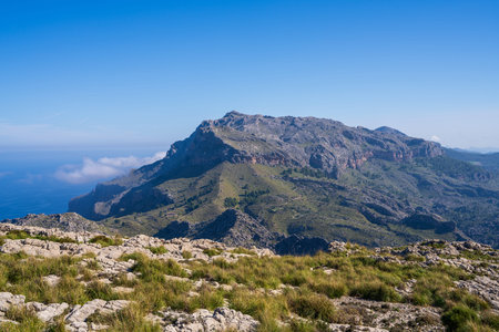 Amazing landscapes of Mallorca. The mountains are covered with greenery, the sea is blue and transparent. Sunny day, clouds over a rocky ridge. Mallorca, Spain, Balearic Islandsの写真素材