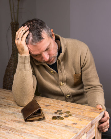 Man looking at empty wallet with small coins. Poor man with no money in wallet. Financial...