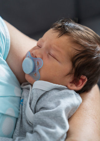 Baby's head in mother's hands. Mom holds a newborn boy, the baby sleeps sweetly. Infant health and...