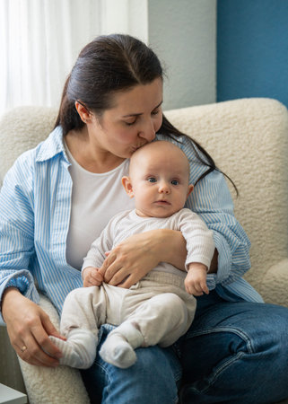 Loving mother with her newborn son. Woman hugs and kisses her baby son, showing love and care....