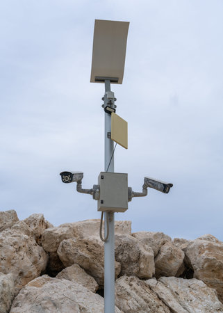 Surveillance cameras hang on pole on city embankment. Security concept is control and protection.