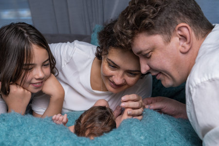 Happy family with a newborn baby. A loving mother and father gently hold their baby son in their...