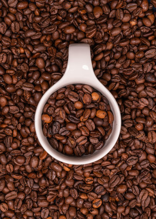 White porcelain cup with coffee beans. Lots of grains. Fragrant tonic drink. Caffeine, cheerfulness,...