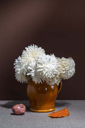 Still life with flowers, yellow leaves on a dark background. White dahlias in a vase, yellow leaves. Place for textの写真素材