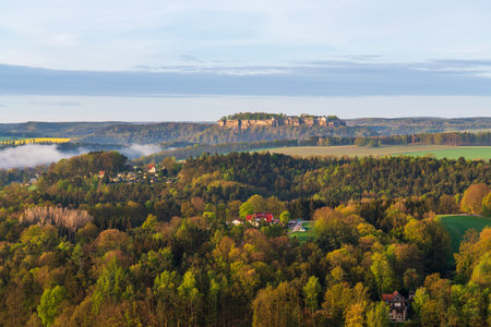 Picturesque view of historic Koenigstein Fortress atop rocky hill in Saxon Switzerland National...