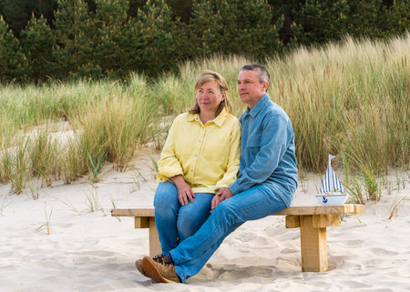 Man and woman are sitting on bench, close to each other. Gently touching each other, showing love. Embankment, vacationの写真素材