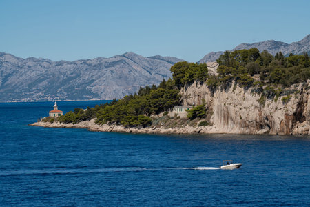 A small boat enters the picturesque port. Amazing coastline. The mountains are covered with...
