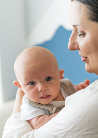 Mother tenderly and lovingly holding her newborn baby boy in her arms. Close up of baby's face