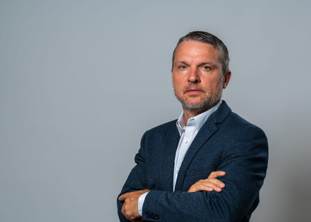 Middle-aged man with confident look in an elegant business suit with arms folded on his chest isolated on white background. image of successful professional. Business concept, career articles.の写真素材