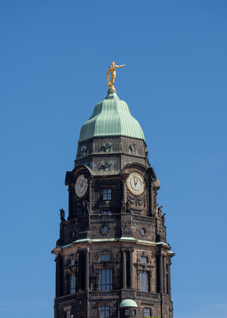 Town hall tower in the center of Dresden with the golden man at the top against the blue skyの写真素材