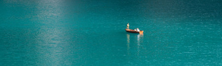 Three people are having fun on a wooden boat. Take a mobile selfie. Blue water. Beautiful nature. Lake Braies. Italy. Dolomites. People in a beautiful placeの写真素材