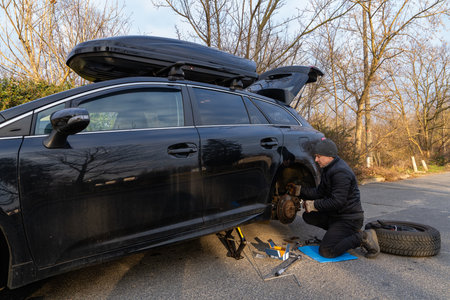 A man is repairing brake pads on a car wheel. He uses a wrench.の写真素材