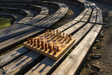 Chess board arranged on bench in city park, representing outdoor recreation, family bonding, quality...