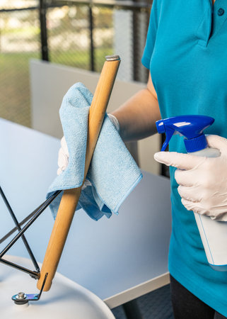 Close up of woman wiping leg of an upside down chair during home cleaning. Concept of hygiene,...