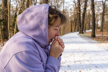 Woman blowing on her hands after holding snow outdoors. Joy, love for life, positive emotions,...