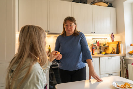Loving mother visits her daughter and helps her while she recovers from an injured arm. Warm family moment showing care, support, everyday life at home.の写真素材