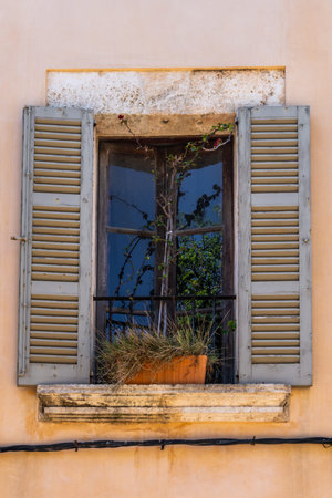 Rustic flower pot with dried grass and flowers sits on windowsill with weathered white shutters. Arta.Traditional Mallorcan architecture and Mediterranean charm.の写真素材