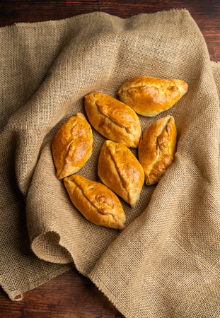 Fresh pies, pirozhki, on burlap fabric. Traditional baked pastry. Home cooking, comfort food, rustic...