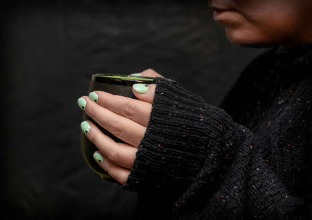 Young woman with nail manicure holds a cup of coffeeの写真素材