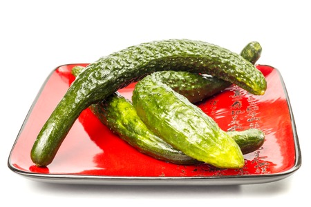 Three long cucumber arranged on a plate red with hieroglyphs on a white backgroundの写真素材