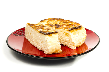 Ð¡heese casserole on a red plate to cut off a piece on a white backgroundの写真素材