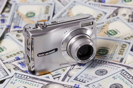 Included silver camera with the lens lying on the dollar billsの写真素材