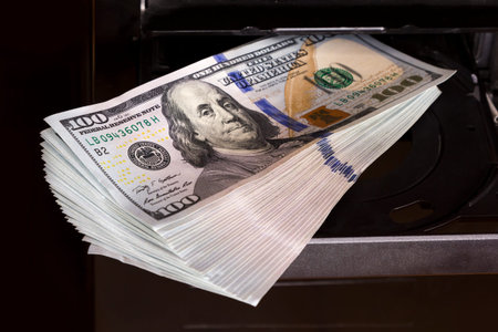 Hundred dollar bills are inserted into computer cdrom