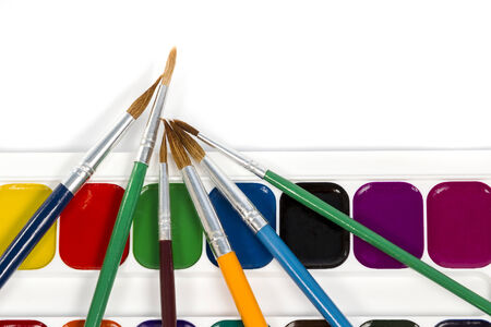 Watercolor paints lying horizontally with a set of different brushes on white backgroundの写真素材