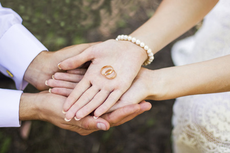 Two golden wedding rings on bride and groom's palmsの写真素材