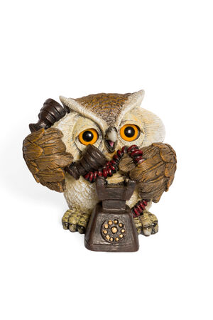 Figurine owl talking on retro phone isolated on white backgroundの写真素材
