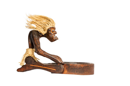 Wooden figurine African shaman performs the rite before the trough isolated on a white backgroundの写真素材
