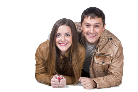 Portrait of loving couple smiling of man and woman in brown leather jacket lying on the floor isolated on white backgroundの写真素材
