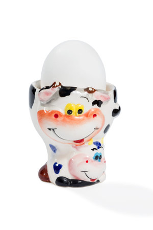 Egg on a ceramic base with faces cows isolated on white background