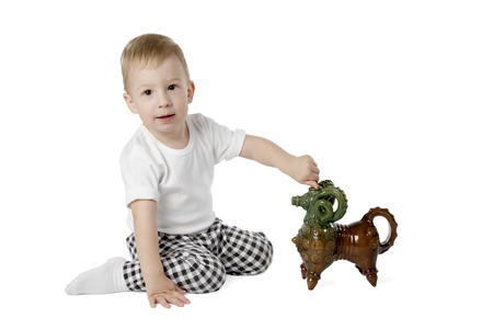 Boy sitting on the floor and plays ceramic toy sheep isolated on a white backgroundの写真素材