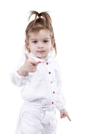 Portrait of a pretty little girl in a white suit with exposed index fingers on both hands isolated on a white backgroundの写真素材
