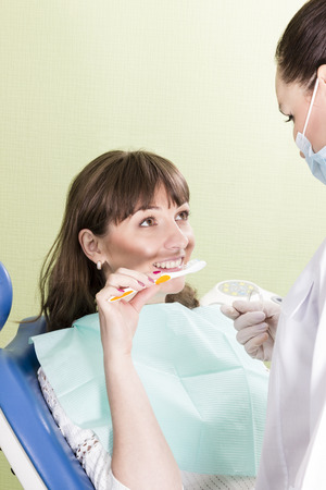 Patient woman shows dentist that she constantly cleans teeth with a toothbrushの写真素材