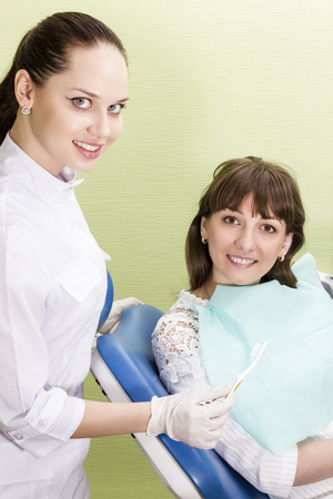 Dentist gives the patient sitting in a chair toothbrushの写真素材