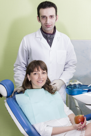 Patient dental clinic sits in a chair and behind him stands dentistの写真素材