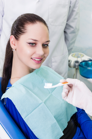 Dentist gives the patient sitting in a chair toothbrushの写真素材