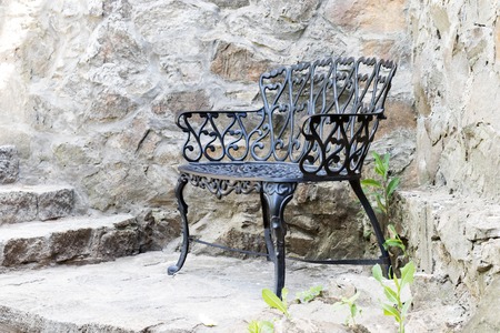 Metallic black vintage empty bench near a wall of stoneの写真素材
