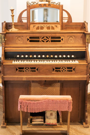Vintage brown American musical organ closeup with a chair